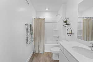 Bathroom with light wood-style floors, vanity, and shower / bath combo with shower curtain