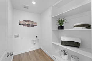 Laundry area featuring light wood finished floors, washer hookup, and electric dryer hookup