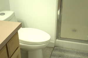 Full bathroom with vanity, a shower stall, and tile patterned flooring