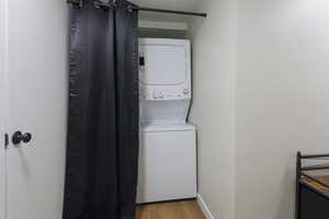 Laundry area featuring light wood finished floors and stacked washer / dryer