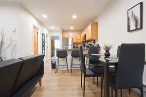 Dining room with light wood finished floors and recessed lighting
