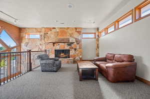 Living area featuring carpet flooring and a stone fireplace