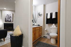 Half bath featuring a textured ceiling, light wood finished floors, vanity, and a fireplace