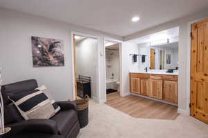 Living area featuring light colored carpet, light wood-style flooring, and recessed lighting