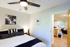 Bedroom with light wood-type flooring, a textured ceiling, a ceiling fan, and recessed lighting
