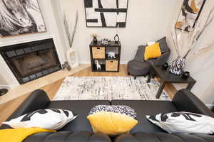 Living room featuring a fireplace with flush hearth and wood finished floors