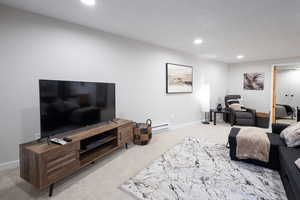 Living area featuring light colored carpet, recessed lighting, and a baseboard radiator