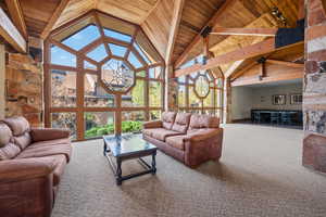 Carpeted living room with high vaulted ceiling and a wood ceiling with exposed beams
