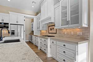 Kitchen featuring white cabinetry, tasteful backsplash, glass insert cabinets, stainless steel fridge, and recessed lighting