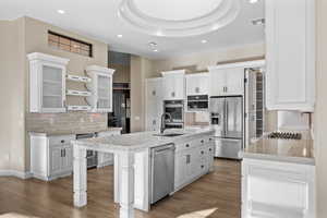 Kitchen with white cabinetry, appliances with stainless steel finishes, tasteful backsplash, open shelves, and light stone countertops
