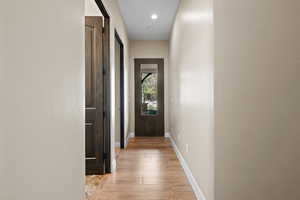 Hall featuring light wood finished floors, a barn door, and recessed lighting