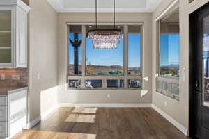 Unfurnished dining area with dark wood-type flooring, plenty of natural light, and a chandelier