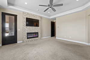 Unfurnished living room featuring a tray ceiling, carpet, recessed lighting, ceiling fan, and a fireplace