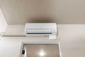 Detailed view of a wall mounted air conditioner and a textured ceiling