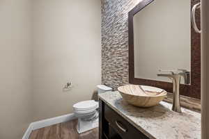 Bathroom with vanity, dark wood-type flooring, and decorative backsplash