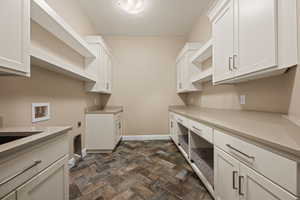 Laundry area with dark stone finish flooring, washer hookup, cabinet space, and electric dryer hookup