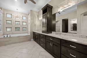 Full bathroom featuring ceiling fan, double vanity, and a bath