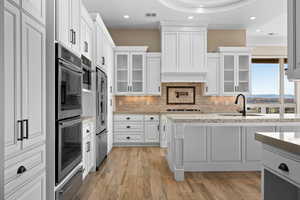 Kitchen featuring backsplash, white cabinetry, glass insert cabinets, appliances with stainless steel finishes, and recessed lighting