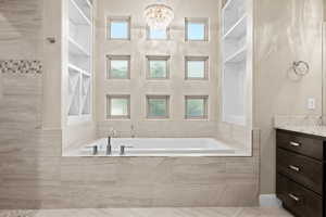 Bathroom with vanity, a bath, and a chandelier
