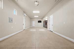 Garage featuring electric panel and baseboards