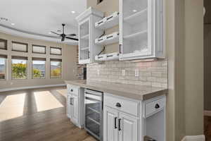 Kitchen with white cabinets, beverage cooler, glass insert cabinets, dark wood finished floors, and recessed lighting