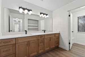 Bathroom on main level with double vanity, dark wood finished floors, and a bath/shower.