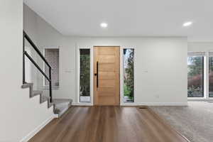 Foyer featuring stairway, wood finished floors, recessed lighting, and carpet flooring