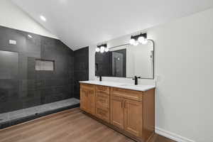 Bathroom featuring  hugewalk in shower, vaulted ceiling, double vanity, and dark wood-type flooring