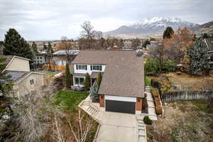 View of front facade featuring a shingled roof, driveway, a chimney, a mountain view, and a garage