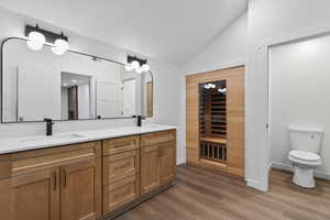 Bathroom featuring a sauna / steam room, double vanity, lofted ceiling, and dark wood-style flooring
