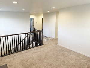 Hallway with an upstairs landing, carpet flooring, and recessed lighting