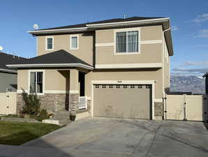 View of front facade featuring a gate, stone siding, stucco siding, and a garage