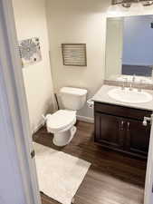 Half bath featuring vanity and dark wood-type flooring