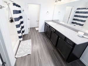 Full bath featuring curtained shower, vanity, and dark wood-style flooring
