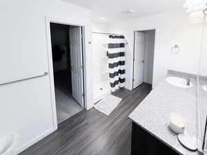 Full bath with vanity, a stall shower, and dark wood finished floors