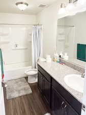 Full bath featuring vanity, shower / bathtub combination with curtain, and dark wood-style floors