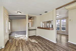 Spare room with dark wood finished floors and vaulted ceiling