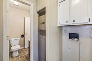 Laundry room featuring washer hookup, a heating unit, dark tile patterned floors, and cabinet space