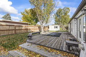 Wooden terrace with a fenced backyard and a storage unit