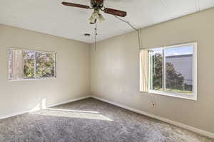 Carpeted spare room featuring baseboards and ceiling fan