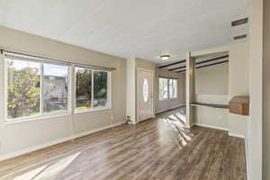 Entryway with wood finished floors and beam ceiling
