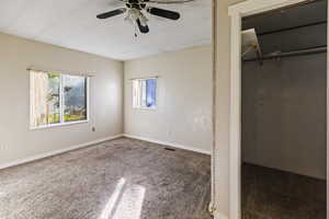 Unfurnished bedroom with carpet, ceiling fan, and a closet