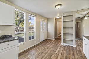 Unfurnished dining area featuring dark wood-type flooring and a ceiling fan