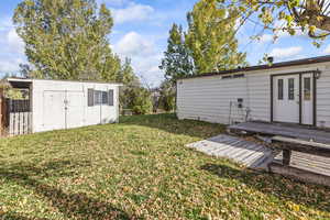View of green lawn featuring a deck and a storage shed