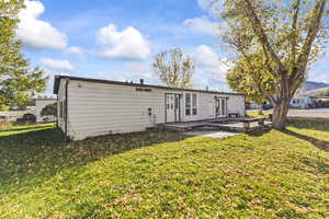 Back of property featuring a lawn, french doors, and a deck