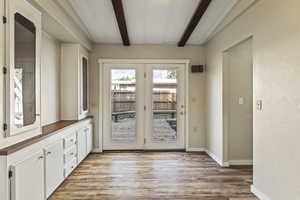 Doorway featuring beamed ceiling and wood finished floors