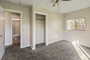 Unfurnished bedroom with dark colored carpet, a closet, and ceiling fan