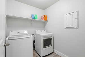 Washroom with light wood-style flooring and washing machine and clothes dryer