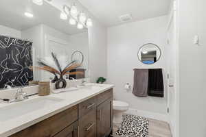 Primary bathroom featuring double vanity, a shower / tub combo with light wood-style floors