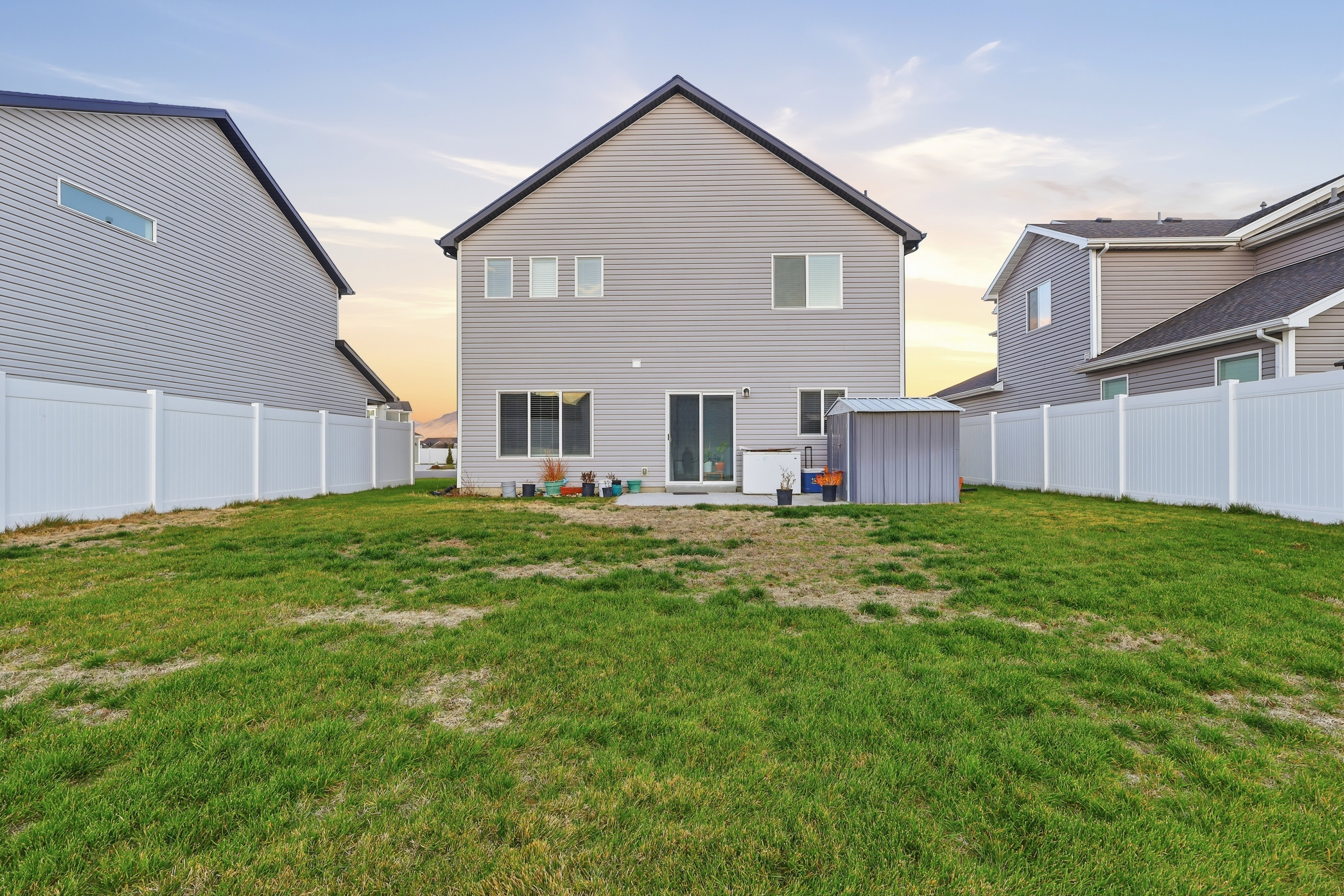 Rear view of property with a partially fenced backyard, a patio, and a storage shed